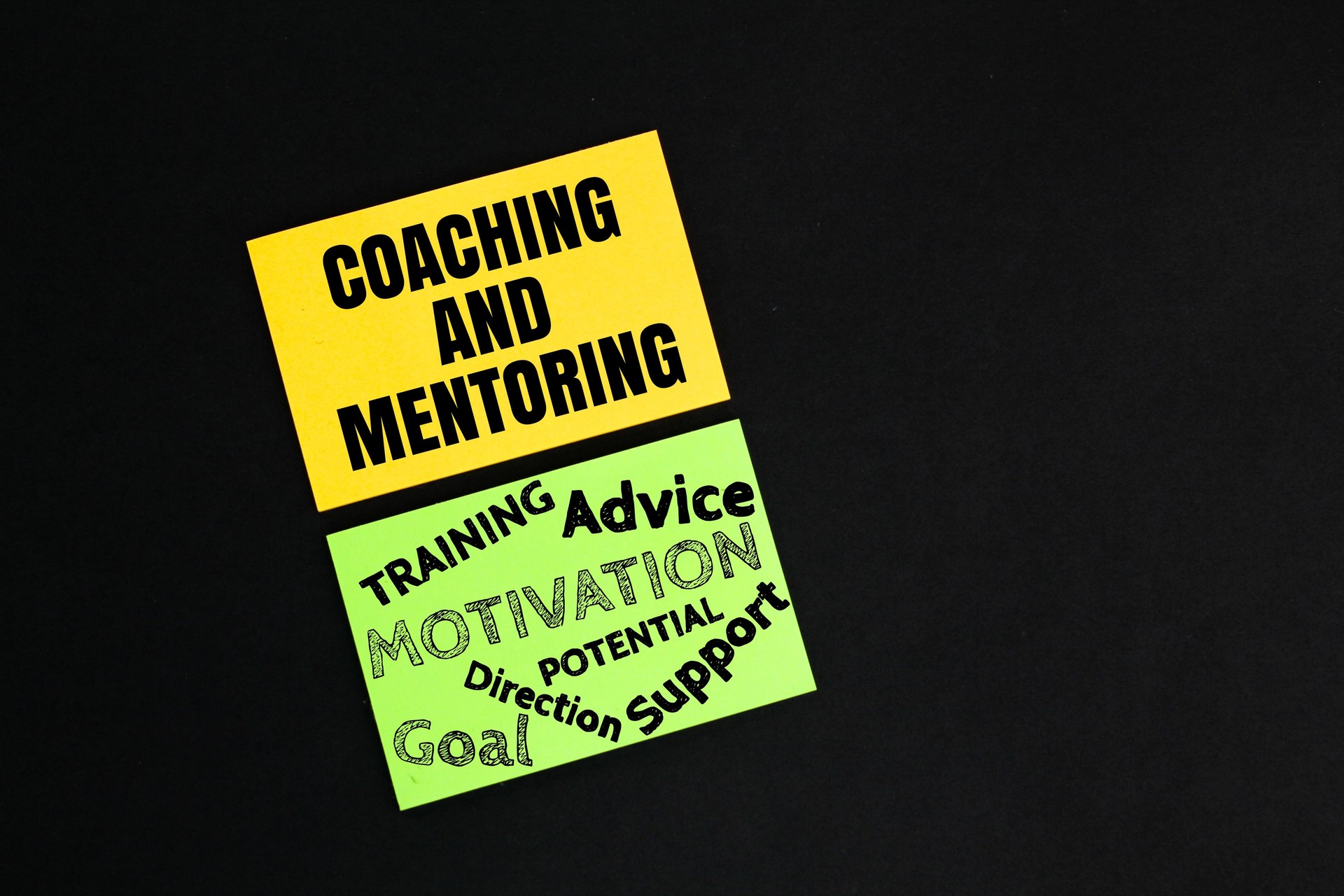 colored paper with the words Coaching and Mentoring. development approaches based on the use of one-to-one conversations to enhance an individual's skills, knowledge or work performance.