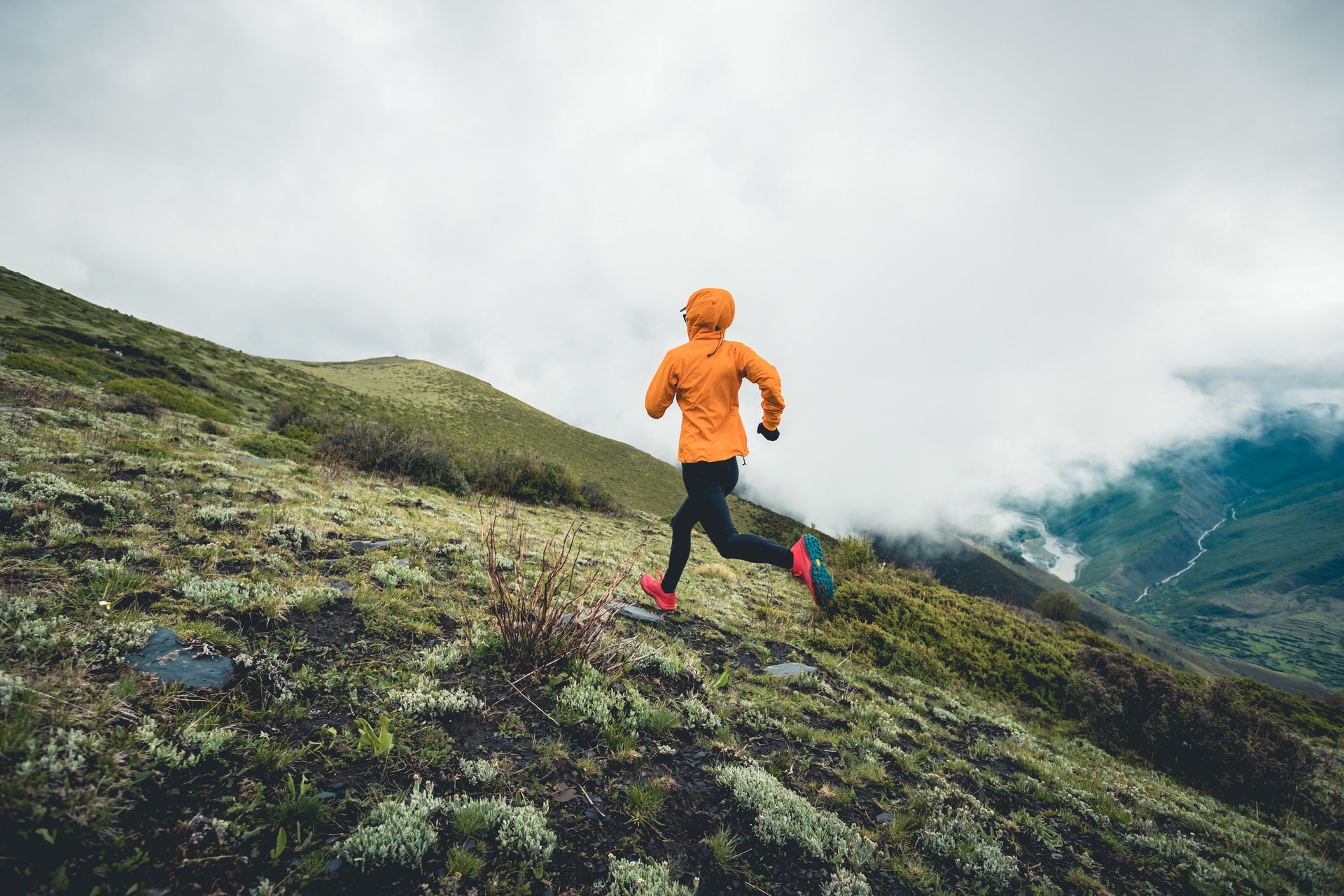 Woman trail runner cross country running to high altitude mountain peak